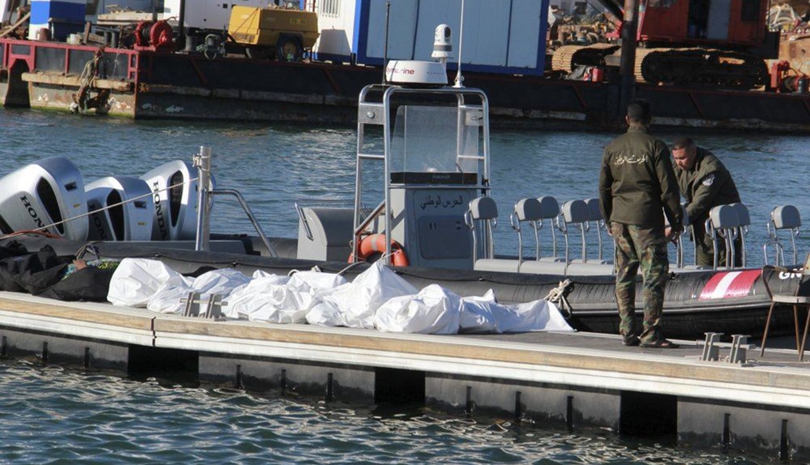 عناصر من خفر السواحل التونسيين يقفون قرب جثث مهاجرين في ميناء صفاقس وسط تونس (24 ك1 2020، أ ب). 