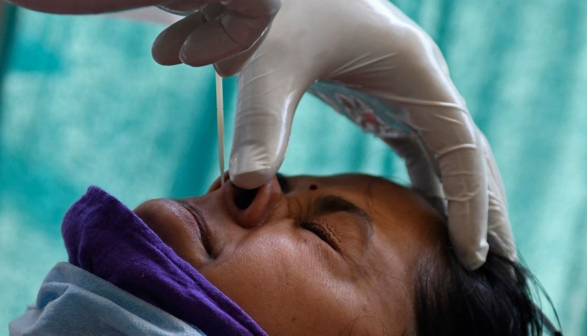 عامل صحي يأخذ مسحة أنفية من امرأة في أمريتسار بالهند (18 نيسان 2021، أ ف ب).