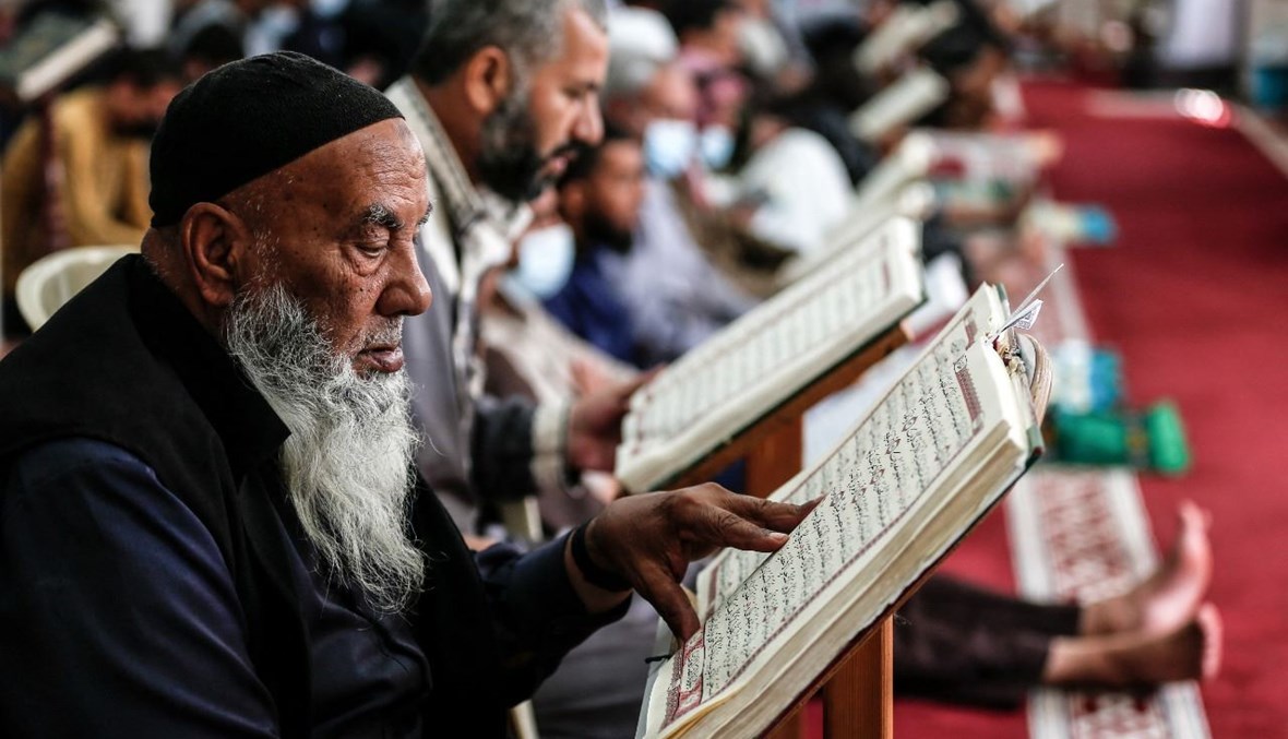 رجل فلسطيني يقرأ مصحفًا في مسجد في مخيم النصيرات وسط قطاع غزة )18 نيسان 2021، ا ف ب). 