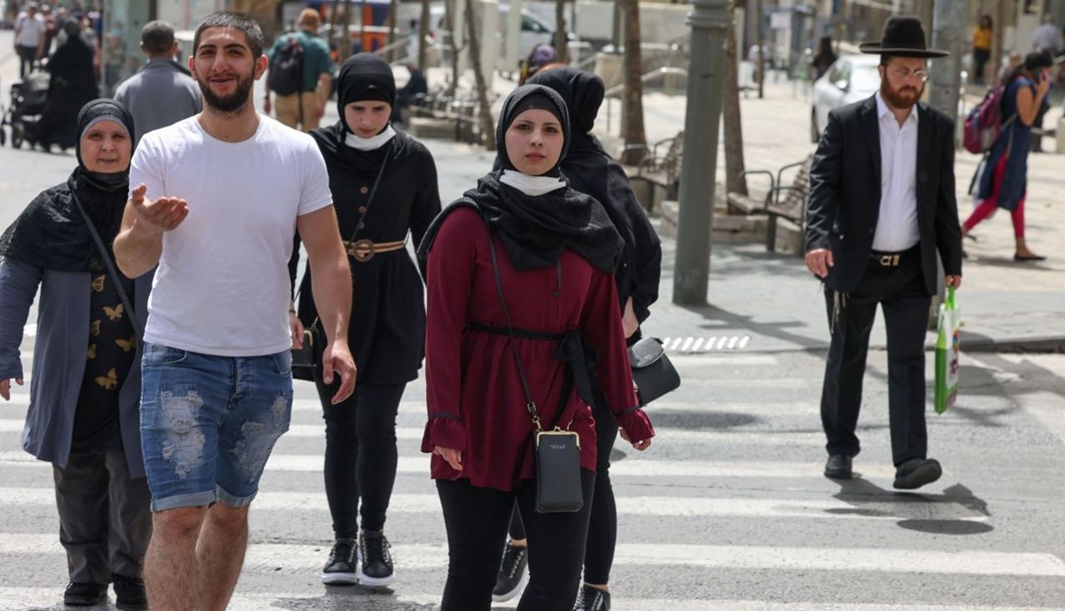 أشخاص يمشون من دون كمامات في أحد شوارع القدس (18 نيسان 2021، ا ف ب). 