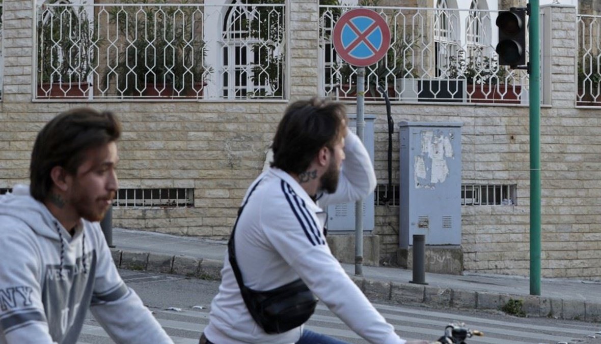 شبّان يركبون دراجاتهم عبر إشارة مرور غير عاملة في العاصمة اللبنانية بيروت (أ ف ب). 