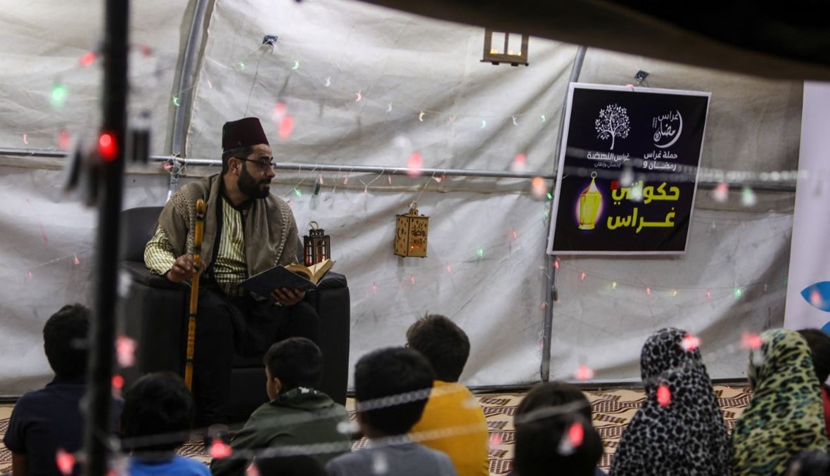أطفال سوريون من أيتام الحرب يستمعون إلى حكواتي في خيمة أقيمت في مخيم العرمل للنازحين عند أطراف بلدة الدانا شمال غرب محافظة إدلب (29 نيسان 2021، أ ف ب). 