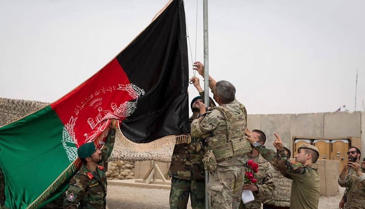 جنود أميركيون وأفغان يرفعون العلم الأفغاني خلال احتفال تسليم في معسكر أنتونيك في ولاية هلمند (2 ايار 2021، أ ف ب). 
