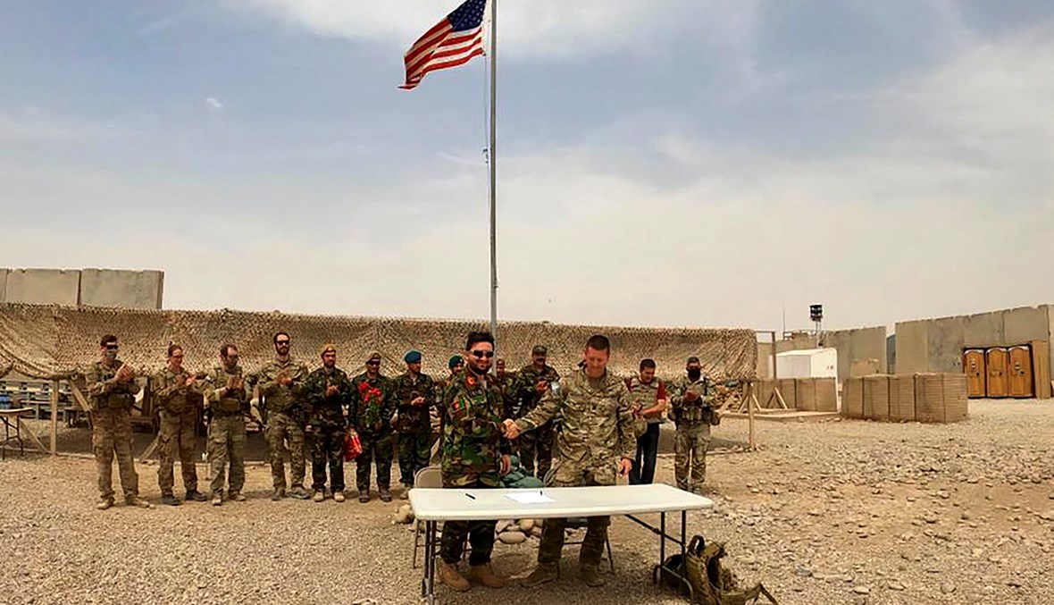 جندي أميريكي وآخر من الجيش الوطني الأفغاني يتصافحان خلال مراسم تسليم الجيش الأفغاني فيلق 215 مايواند في معسكر أنتونيك. في ولاية هلمند (أ ف ب).