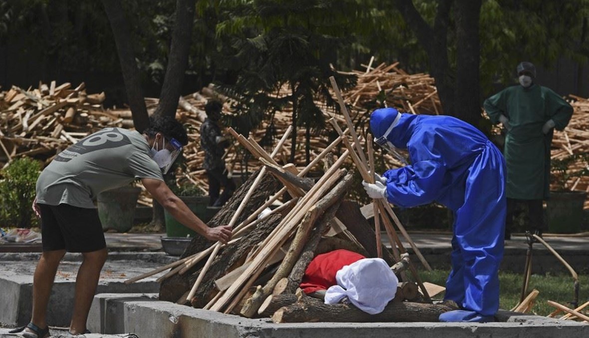أقارب يجهزون مكاناً لحرق جثة أحد المتوفين بكورونا في نيودلهي الاثنين. (أ ف ب)