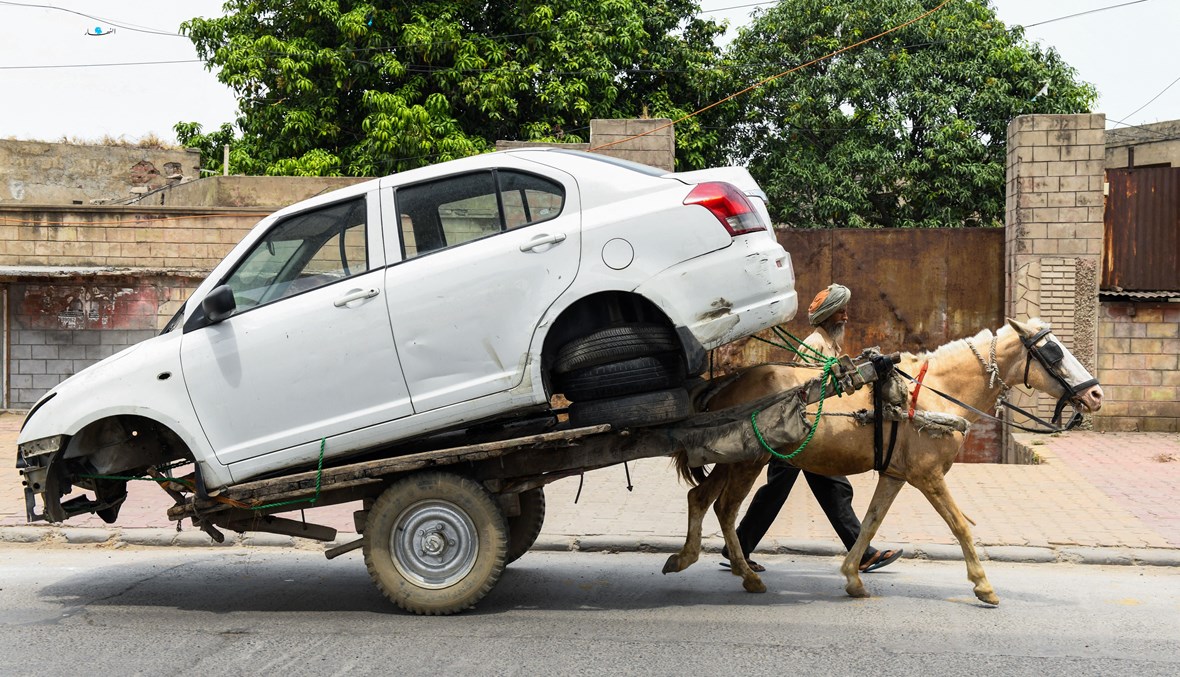 رجل ينقل سيارة على عربة يجرها حصان (تعبيرية - أ ف ب).