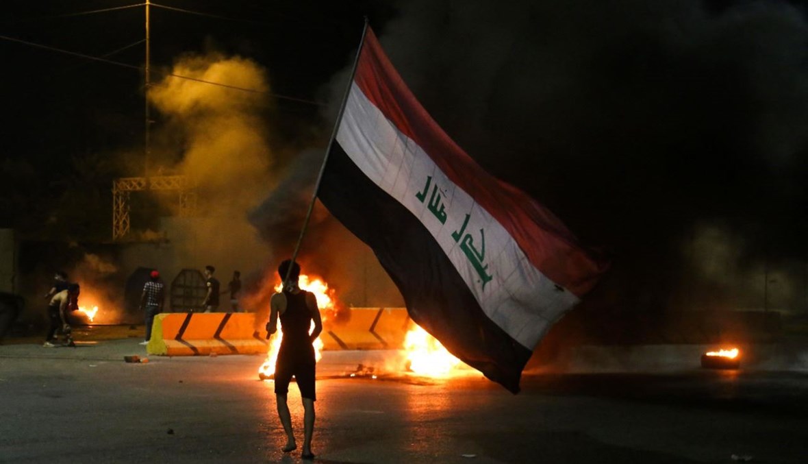 متظاهرون عراقيون يحرقون الإطارات أمام مقر محافظة كربلاء وسط مدينة كربلاء بعد اغتيال الوزني (9 ايار 2021، أ ف ب). 