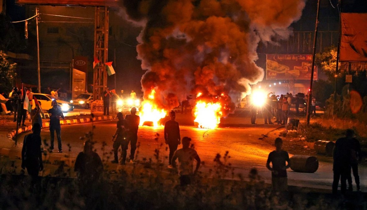 متظاهرون فلسطينيون يحرقون الإطارات خلال اشتباكات مع قوات الأمن الإسرائيلية عند حاجز حوارة جنوب مدينة نابلس في الضفة الغربية المحتلة (8 ايار 2021، أ ف ب). 