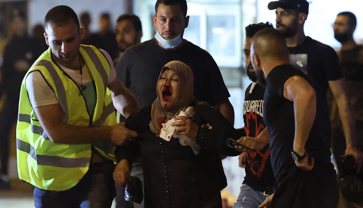 فلسطينيون يساعدون امرأة اصيبت خلال اشتباكات مع قوات الأمن الإسرائيلية في البلدة القديمة بالقدس (8 ايار 2021، أ ف ب). 