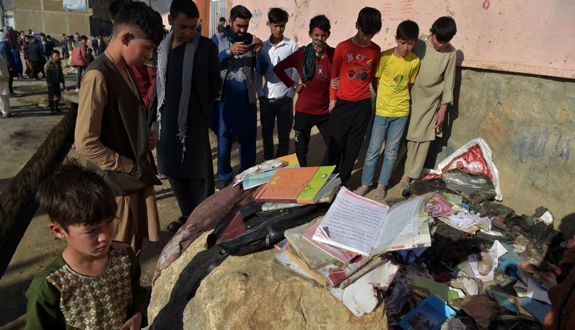 أطفال ينظرون الى حقائب مدرسية وكتب لضحايا تفجيرات استهدفت مدرسة للبنات في داشت إي بارشي في ضواحي كابول (9 ايار 2021، أ ف ب). 