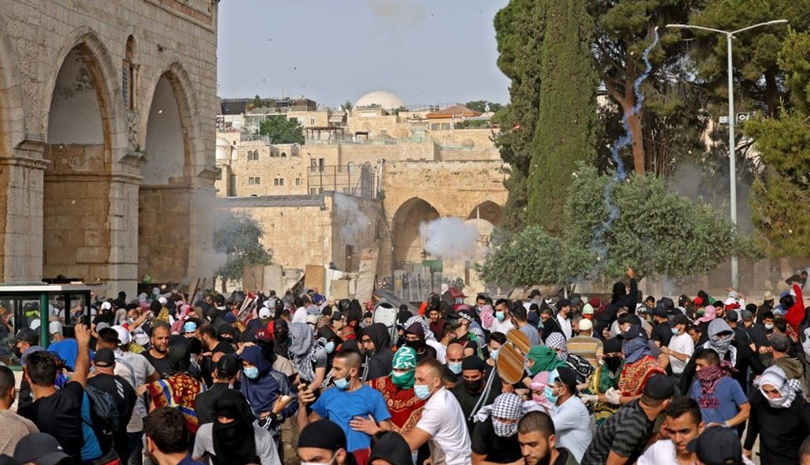 فلسطينيون يحاولون الإحتماء خلال المواجهات مع القوات الاسرائيلية في مجمع المسجد الأقصى بالقدس الشرقية أمس.(أ ف ب)