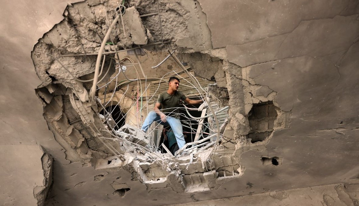 فلسطيني يتفقد الأضرار التي سببتها غارة جوية إسرائيلية على البنك الوطني الإسلامي التابع لحركة حماس في خان يونس جنوب قطاع غزة (13 ايار 2021، أ ف ب). 