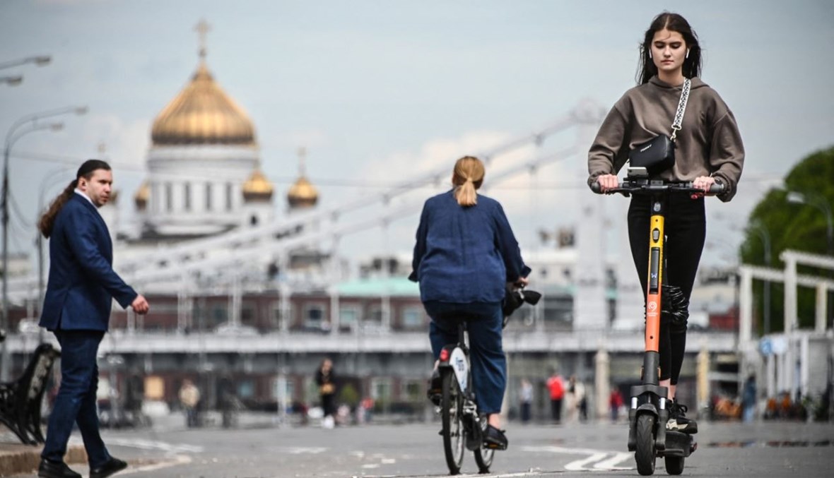 امرأة تركب السكوتر على جسر نهر موسكفا في موسكو (14 ايار 2021، أ ف ب). 