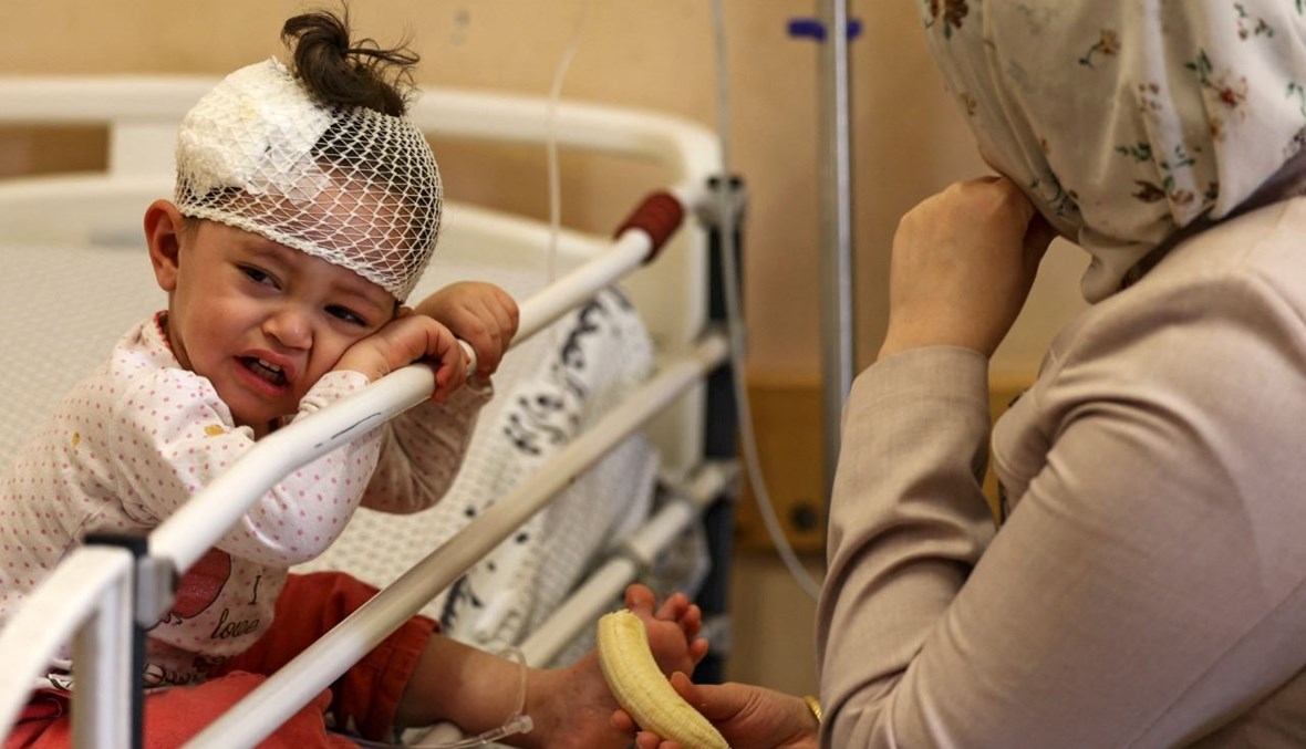 أم فلسطينية تجلس مع طفلتها المصابة في الغارات الإسرائيلية على غزة ، في مستشفى الشفاء بمدينة غزة (16 ايار 2021، أ ف ب). 