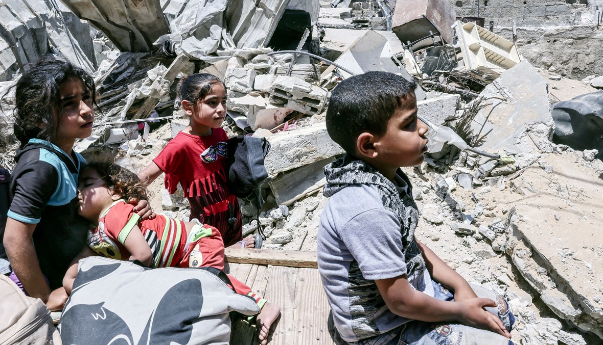 أطفال في غزّة يجلسون على أنقاض بيتهم المدمّر (أ ف ب).