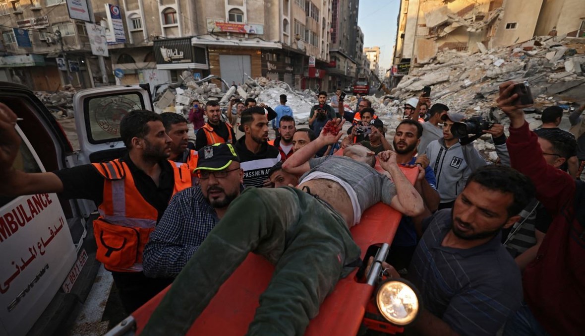 فلسطينيون يحملون رجلا بعد انقاذه من تحت أنقاض مبنى دمرته غارات إسرائيلية في غزة (16 ايار 2021، ا ف ب). 
