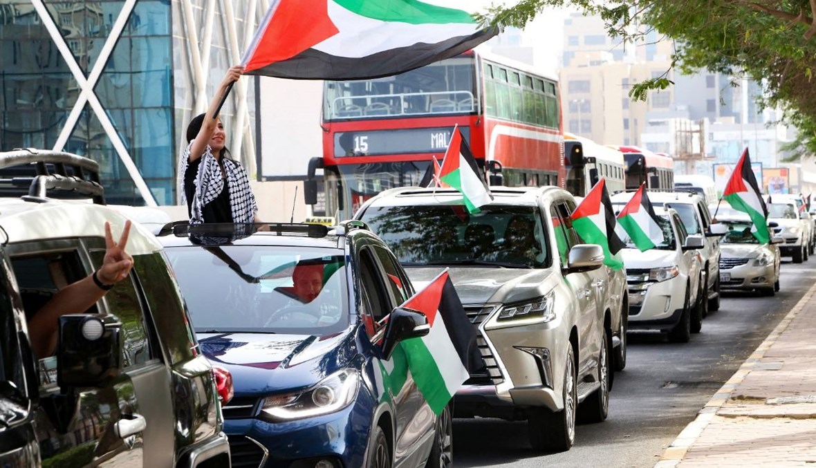 كويتيون يرفعون الأعلام الفلسطينية خلال "حملة تضامن" مع الفلسطينيين (15 ايار 2021، أ ف ب). 