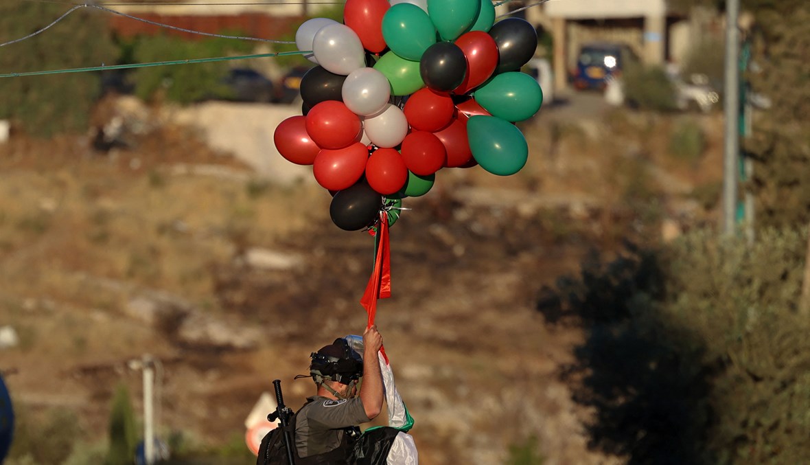 عنصر من قوات الأمن الإسرائيلية يزيل بالونات نصبها فلسطينيون في حي الشيخ جراح بالقدس الشرقية (أ ف ب).