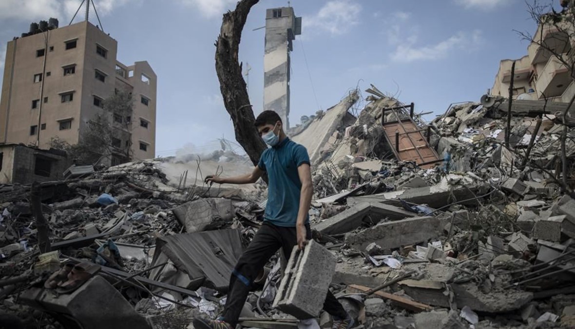 فلسطيني فوق ركام مبنى من ستة طوابق دمرته غارة إسرائيلية في مدينة غزة أمس.(أ ب)