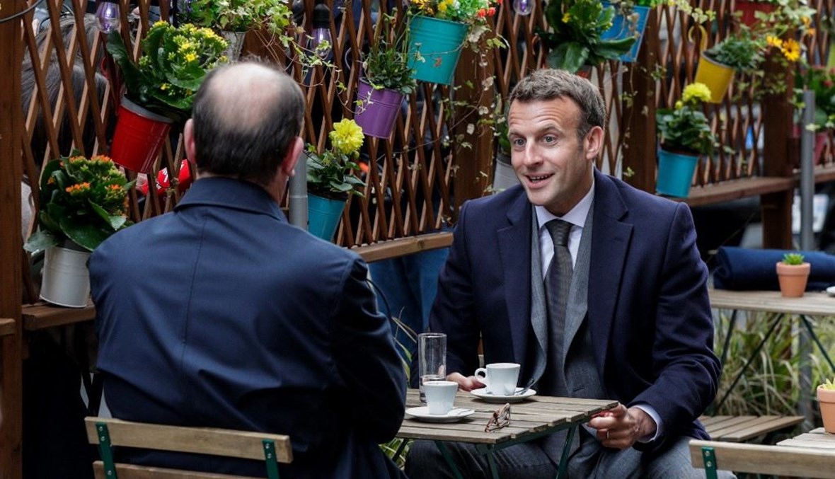 ماكرون ورئيس الوزراء الفرنسي يتناولان القهوة في مقهى بباريس (أ ف ب).