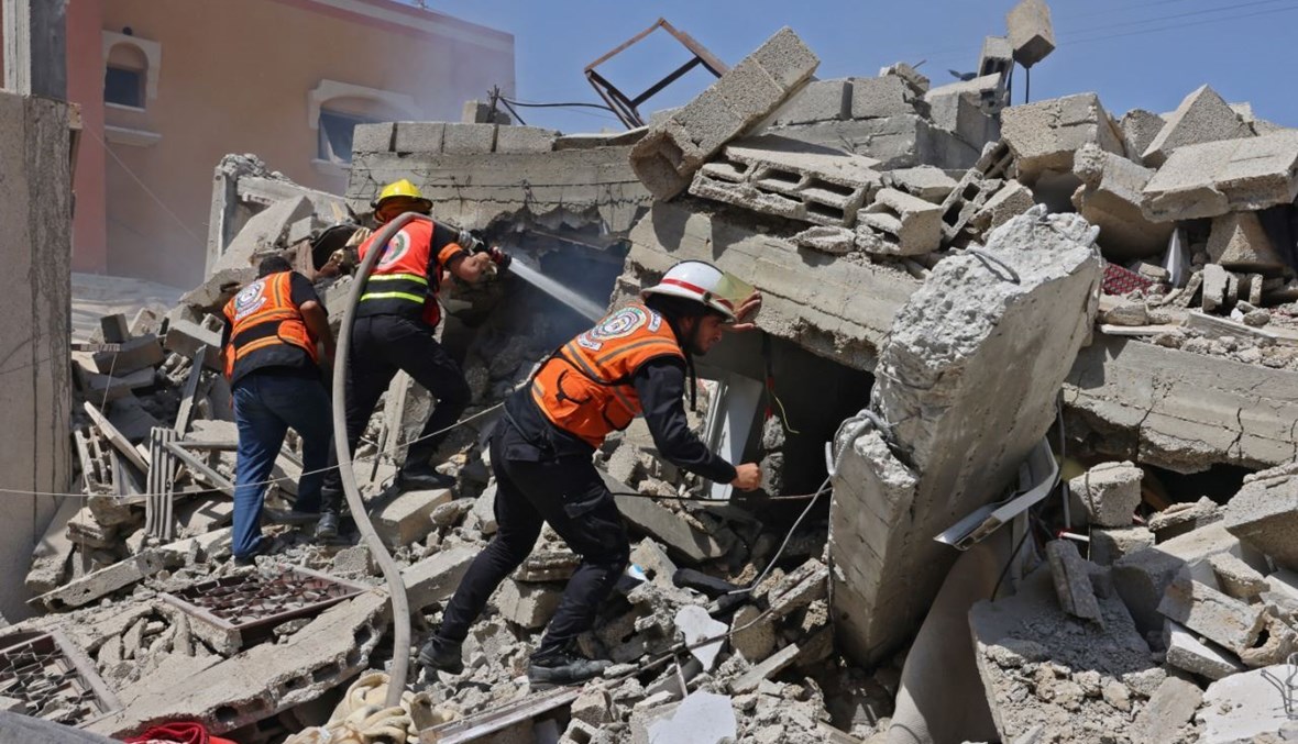 عمال إنقاذ فلسطينيون تجمعوا حول انقاض مبنى دمرته غارة جوية إسرائيلية على رفح جنوب قطاع غزة (20 ايار 2021، أ ف ب).