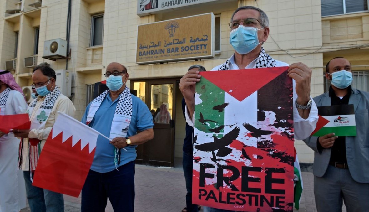 محامون بحرينيون يحملون لافتات خلال تجمع تضامني مع الفلسطينيين أمام مقر جمعية المحامين البحرينية في العاصمة المنامة (20 ايار 2021، أ ف ب). 
