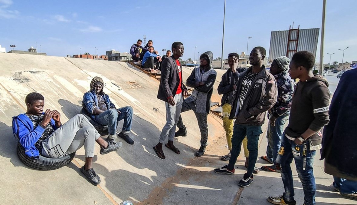 مهاجرون أفارقة ينتظرون تحت جسر في العاصمة الليبية طرابلس بحثاً عن عمل (6 آذار 2021، أ ف ب). 