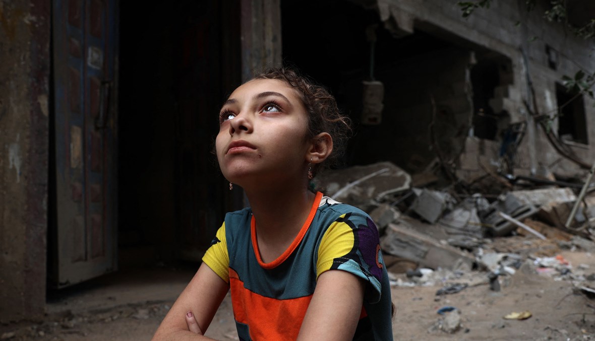 طفلة فلسطينية تجلس أمام منزلها الذي دمره القصف الإسرائيلي في مدينة غزة (تعبيرية - أ ف ب).