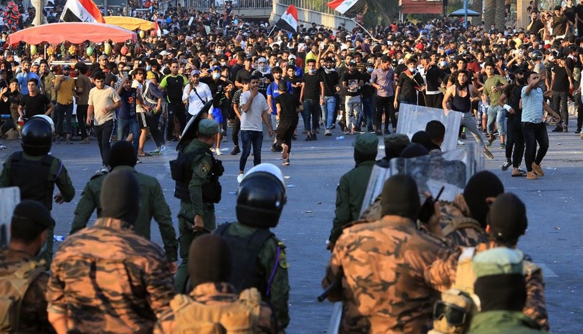قوى الأمن في مواجهة متظاهرين في ساحة التحرير ببغداد الثلثاء.   (أ ف ب)