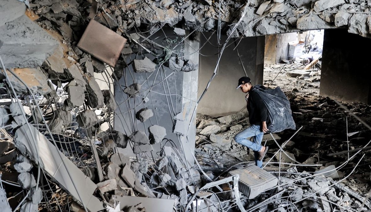 شاب فلسطيني يبحث عن أشياء قابلة للإصلاح، في أنقاض مبنى دمره القصف الاسرائيلي على غزة (27 ايار 2021، أ ف ب). 