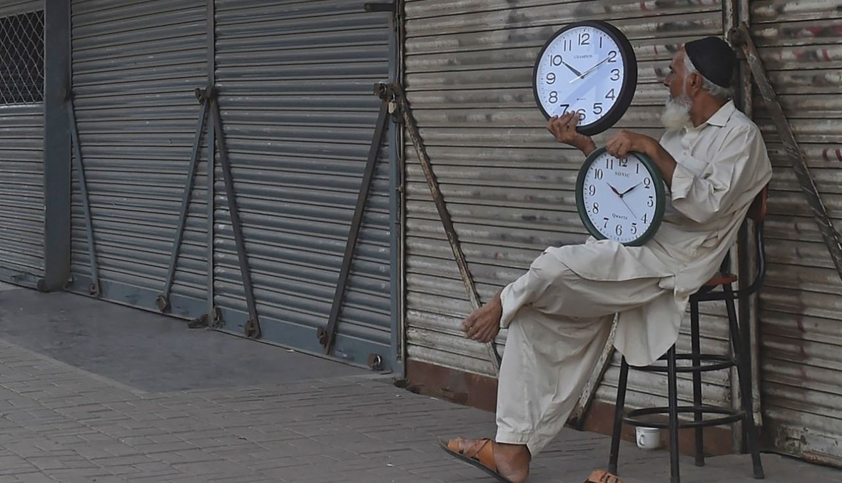 بائع متجول يحمل ساعات حائط لبيعها في كراتشي (28 ايار 2021، أ ف ب). 