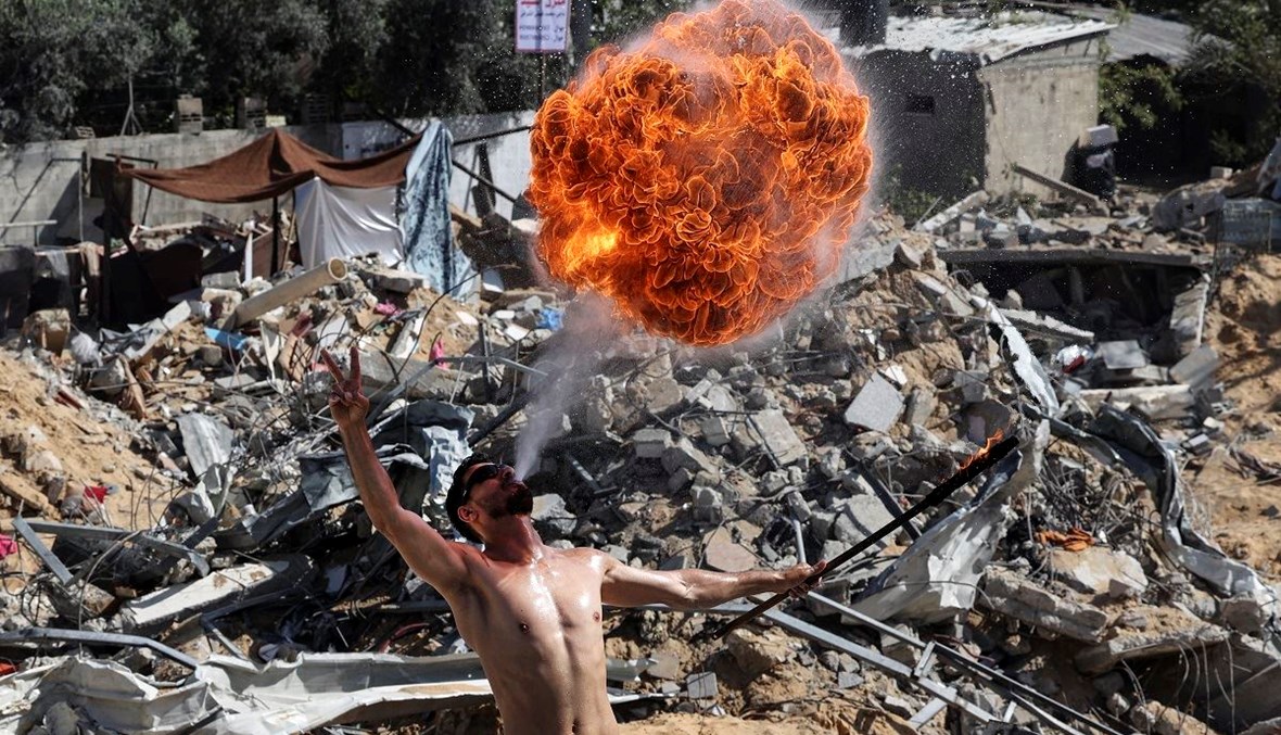 شاب فلسطيني من فريق "بار وولف" الرياضي يقدّم عرضاً بالنار فوق أنقاض مبنى دمرته الضربات الجوية الإسرائيلية في بيت لاهيا (أ ف ب).