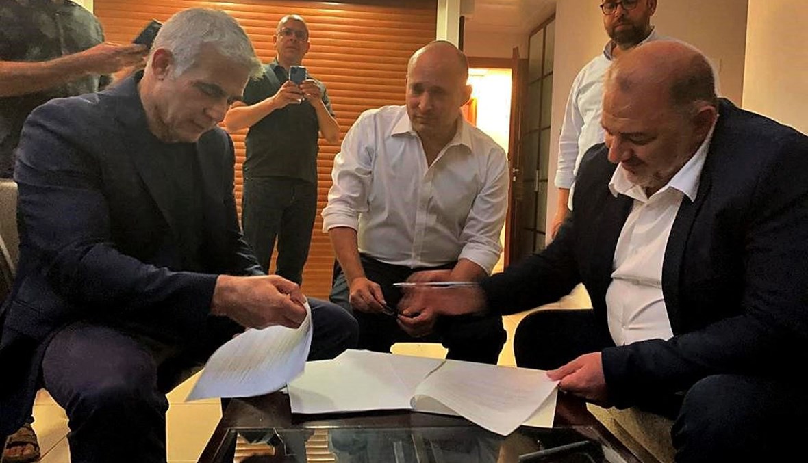 عباس (إلى اليمين) موقعا اتفاقية ائتلافية مع لابيد (يسار) وبينيت في رمات غان بالقرب من تل أبيب (2 حزيران 2021، أ ف ب).