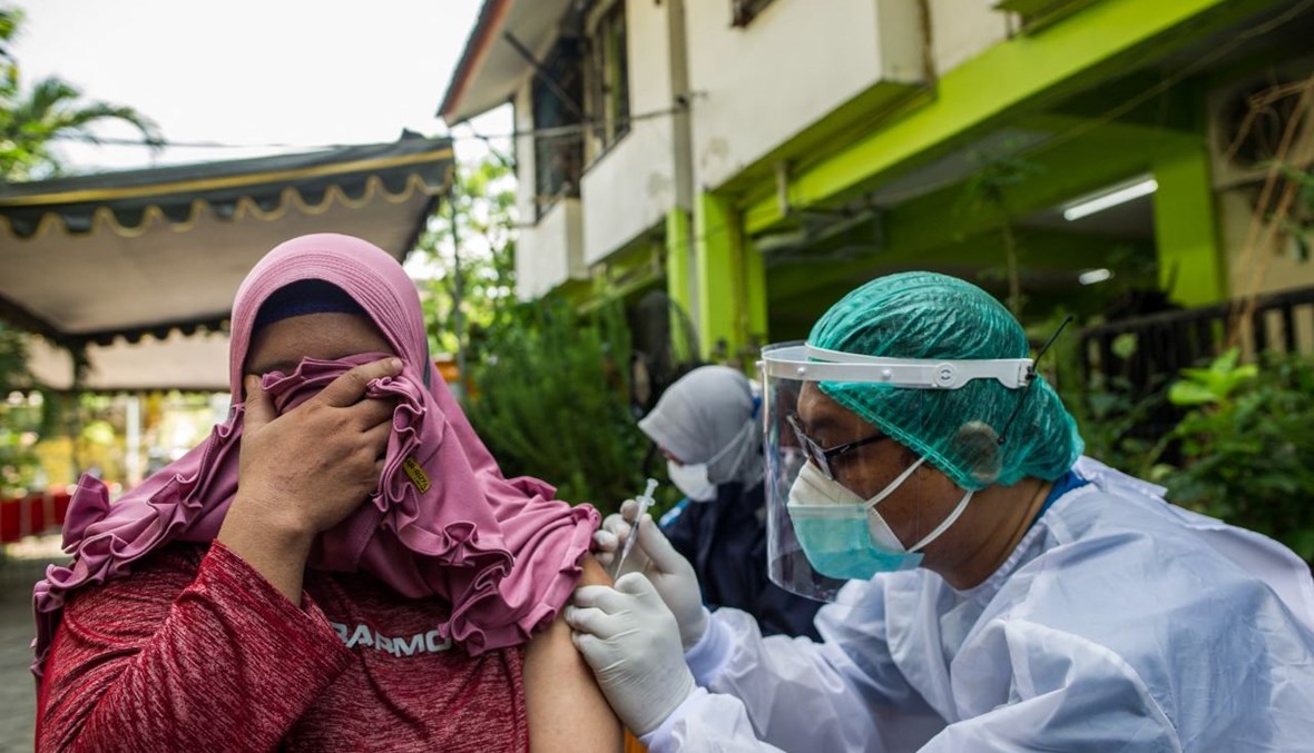 امرأة تتلقى لقاح كورونا في سورابايا في اندونيسيا (6 حزيران 2021، أ ف ب). 