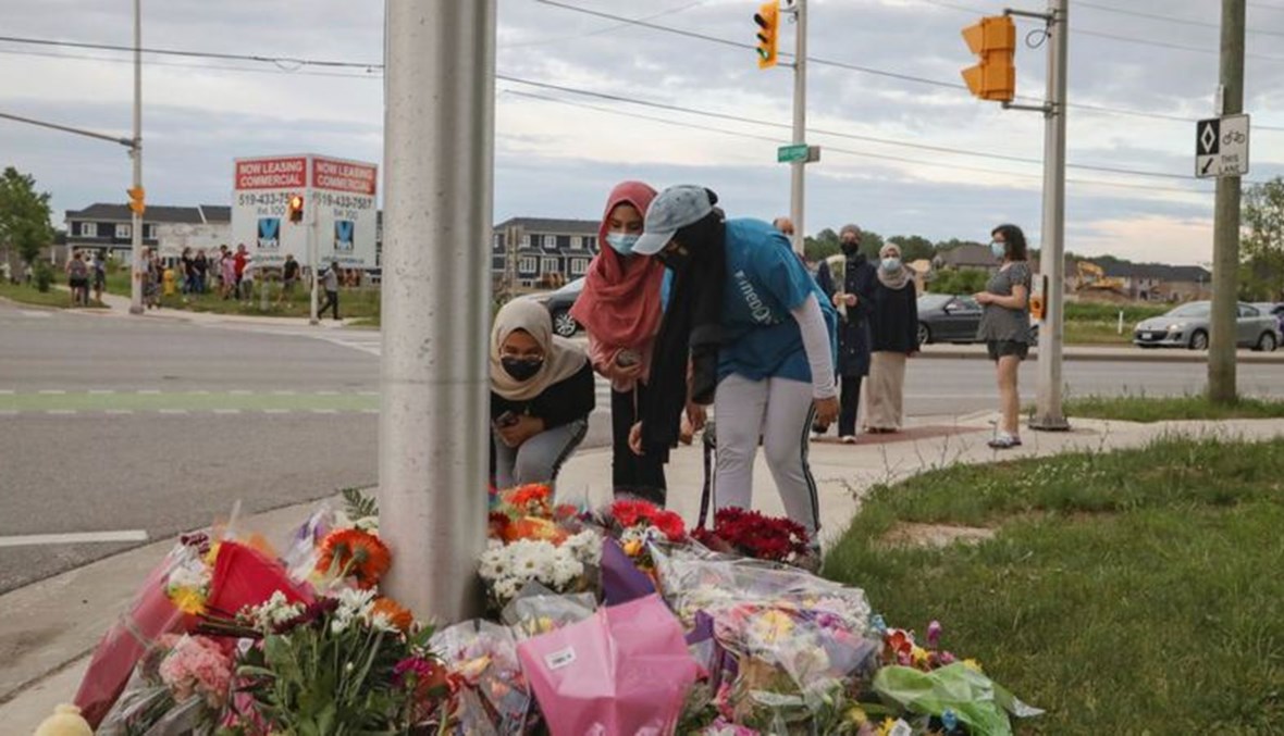 أشخاص يضعون الورود على نصب موقت للضحايا في موقع الحادث بمدينة لندن في جنوب مقاطعة أونتاريو الكندية.    