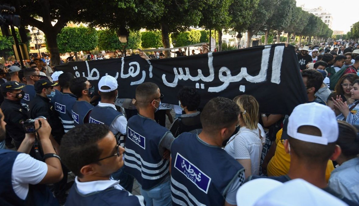 شرطيون تونسيون في مواجهة متظاهرين يحتجون على عنف الشرطة في شارع الحبيب بورقيبة بالعاصمة تونس (12 حزيران 2021، أ ف ب). 