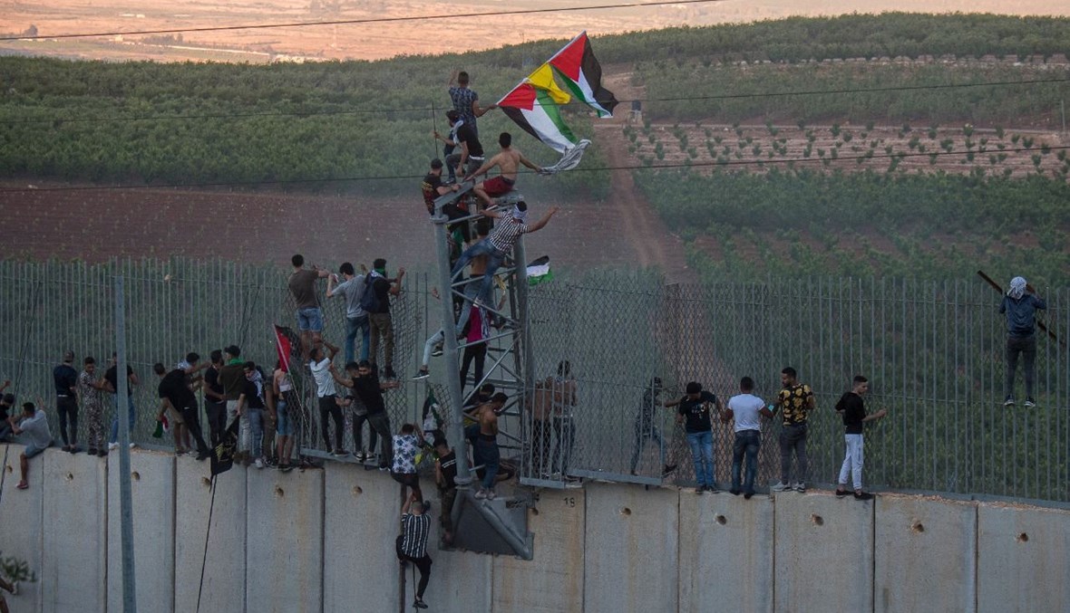 شبّان يتسلّقون جدار الإسمنت الفاصل عند الحدود الجنوبية (نبيل اسماعيل).