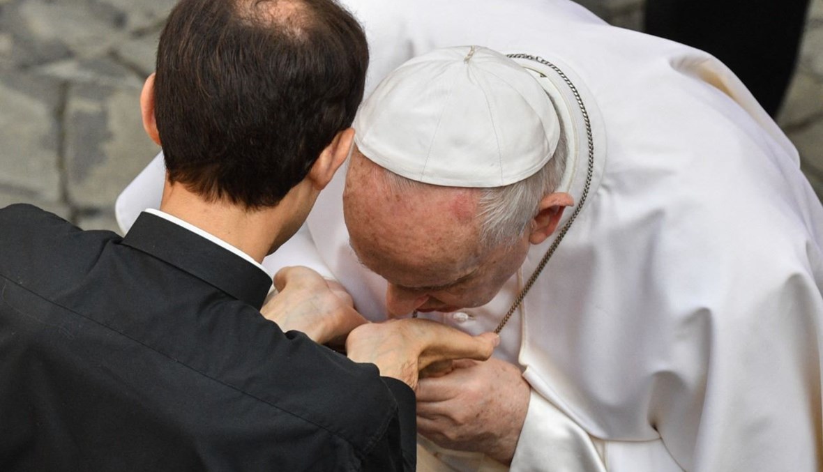 البابا فرنسيس يقبّل كفي كاهن خلال لقائه العام الأسبوعي في ساحة سان داماسو في الفاتيكان (16 حزيران 2021، أ ف ب). 
