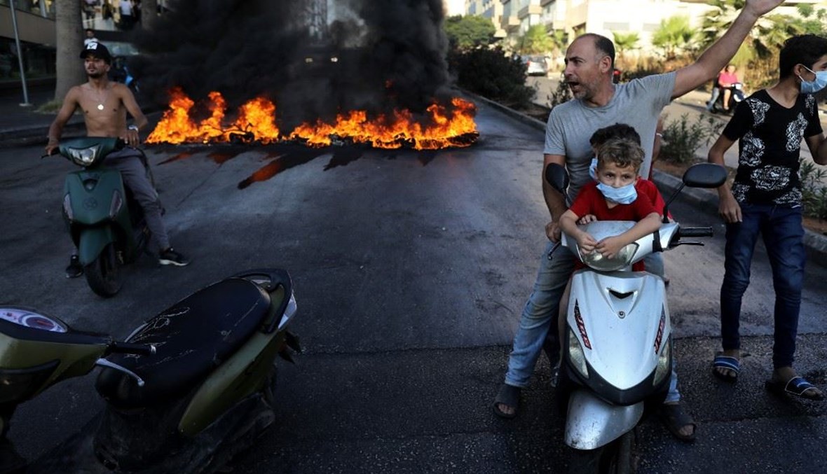 مواطن على دراجته مع طفلين خلال الاحتجاجات (أ ف ب).
