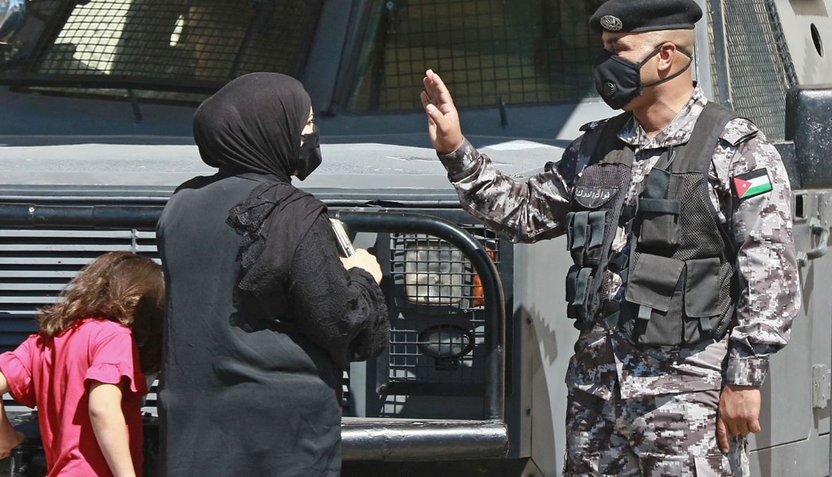 شرطي يتحدث الى امرأة أمام مقر محكمة أمن الدولة في عمان (21 حزيران 2021، ا ف ب). 