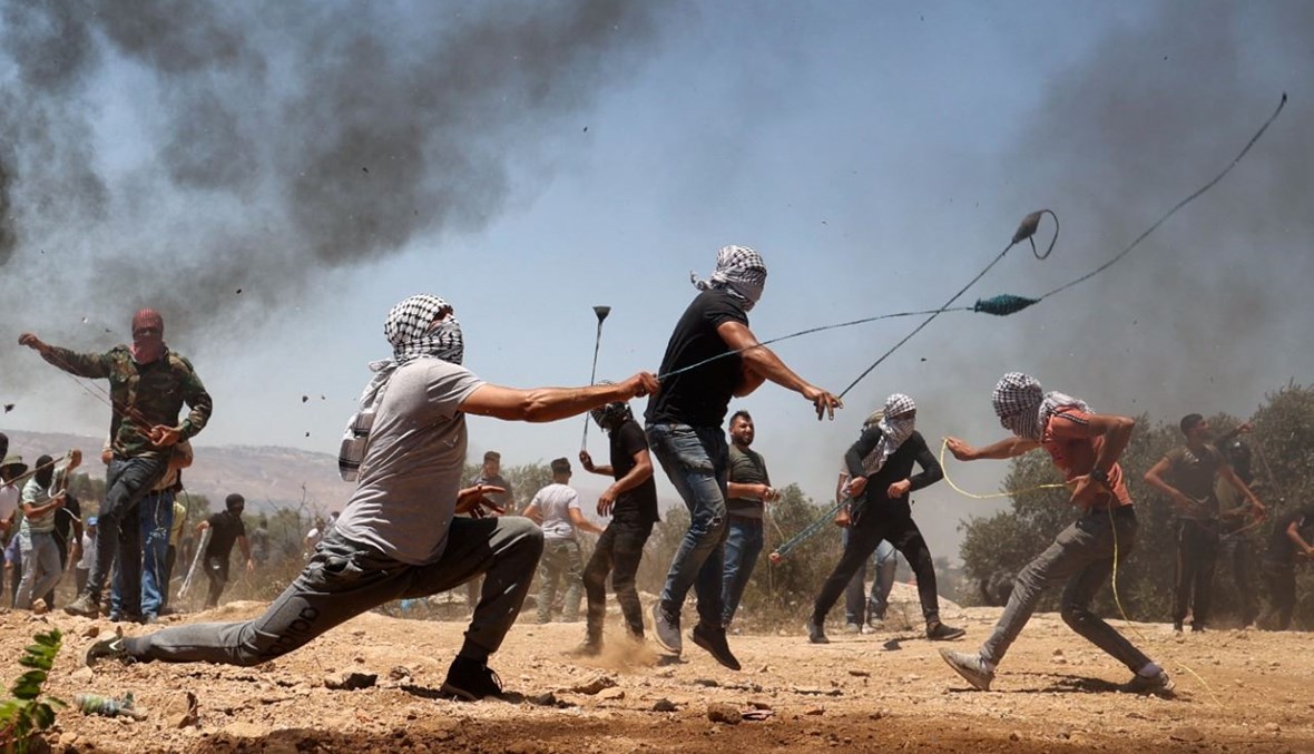متظاهرون فلسطينيون خلال مواجهات مع قوات الأمن الإسرائيلية في بلدة بيتا بالقرب من مدينة نابلس في الضفة الغربية المحتلة (2 تموز 2021، أ ف ب). 