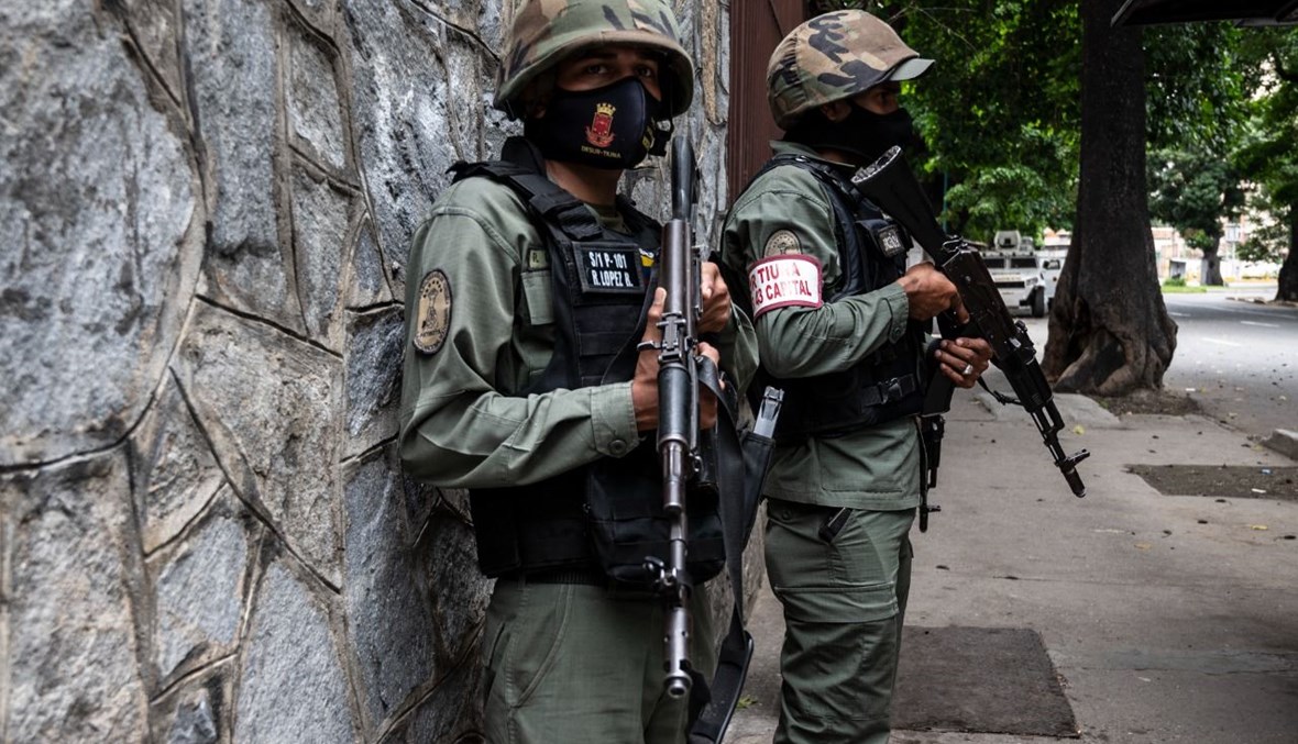 عنصران من الحرس الوطني يقفان في أحد الشوارع خلال الاشتباكات مع عصابة إجرامية في محيط حي لا كوتا 905 في كاراكاس (8 تموز 2021، أ ف ب). 