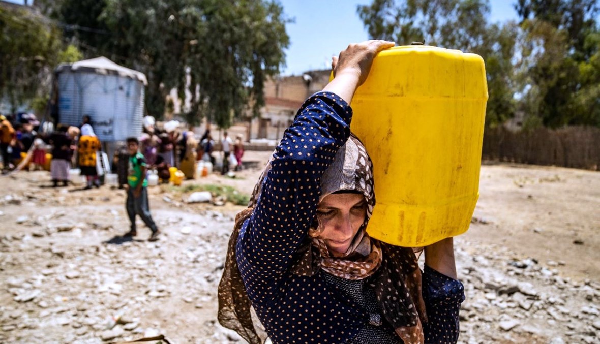 امرأة سورية تحمل حاوية مياه قدمتها منظمة "اليونيسف" في مدينة الحسكة شمال شرق سوريا (8 تموز 2021، أ ف ب). 