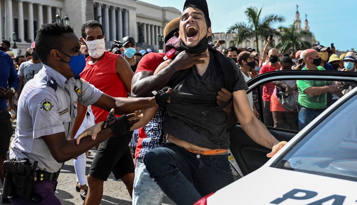 شرطيون يوقفون رجلا خلال تظاهرة في هافانا ضد حكومة الرئيس الكوبي (11 تموز 2021، أ ف ب). 