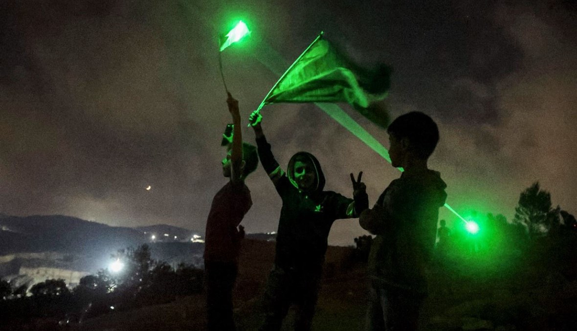شبان فلسطينيون يستخدمون مشاعل الليزر خلال تظاهرة في بلدة بيتا بالقرب من نابلس بالضفة الغربية المحتلة، احتجاجا على بؤرة المستوطنين الإسرائيليين في إفيتار (13 تموز 2021، أ ف ب). 