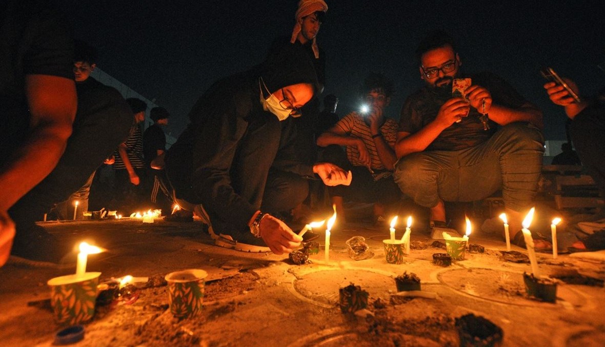 إضاءة الشموع أمام مستشفى الحسين في العراق (أ ف ب).