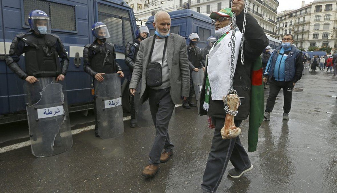 رجل يحمل عظمة وهو يصيح "هذا ما تبقى لمن يصوتون للرئيس" بينما يتظاهر الجزائريون في الجزائر العاصمة لإحياء الذكرى الثانية لحركة الحراك (22 شباط 2021، أ ب). 