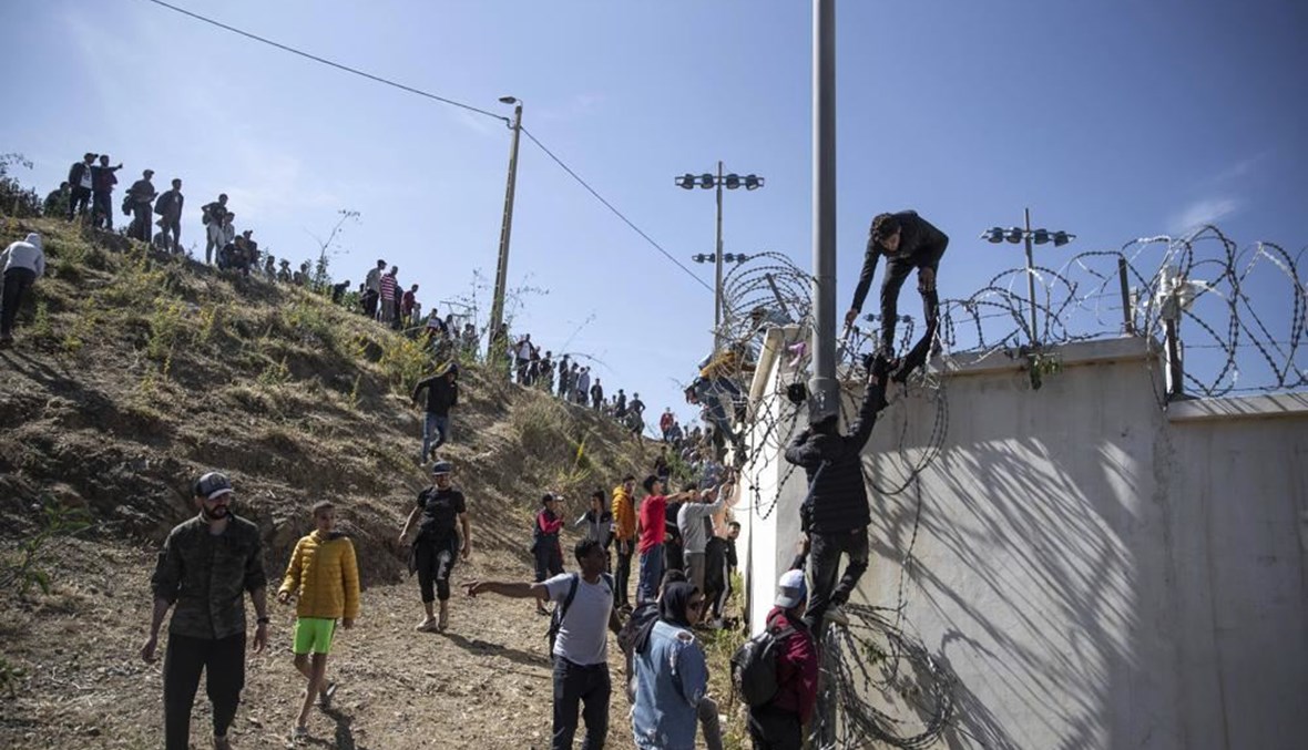 أشخاص يتسلقون سياجًا في المنطقة الواقعة على الحدود الإسبانية -المغربية، خارج جيب سبتة الإسباني (18 ايار 2021، أ ب). 