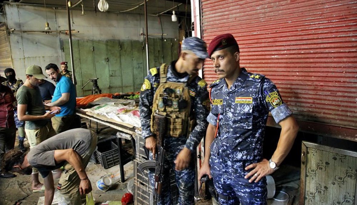 رجال أمن عراقيون انتشروا في موقع تفجير في سوق الوحيلات بمدينة الصدر بالعراق (19 تموز 2021، أ ب). 
