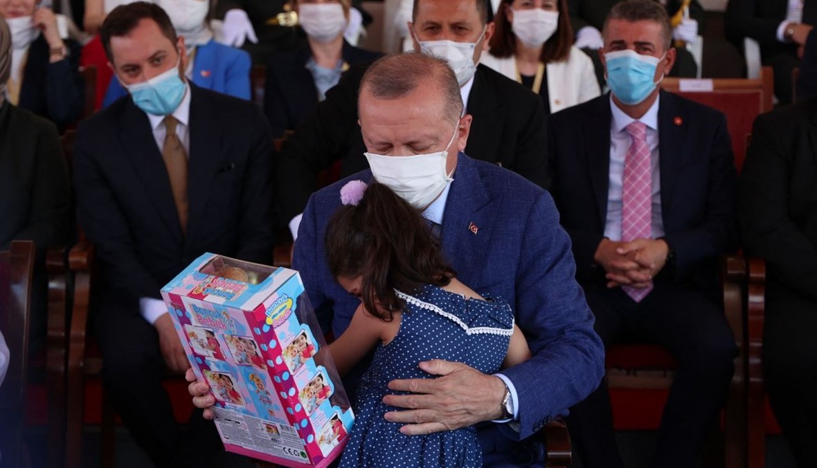 إردوغان يقدم هدية إلى فتاة خلال مشاركته في عرض عسكري في الجزء الشمالي من نيقوسيا في جمهورية شمال قبرص التركية (20 تموز 2021، أ ف ب).